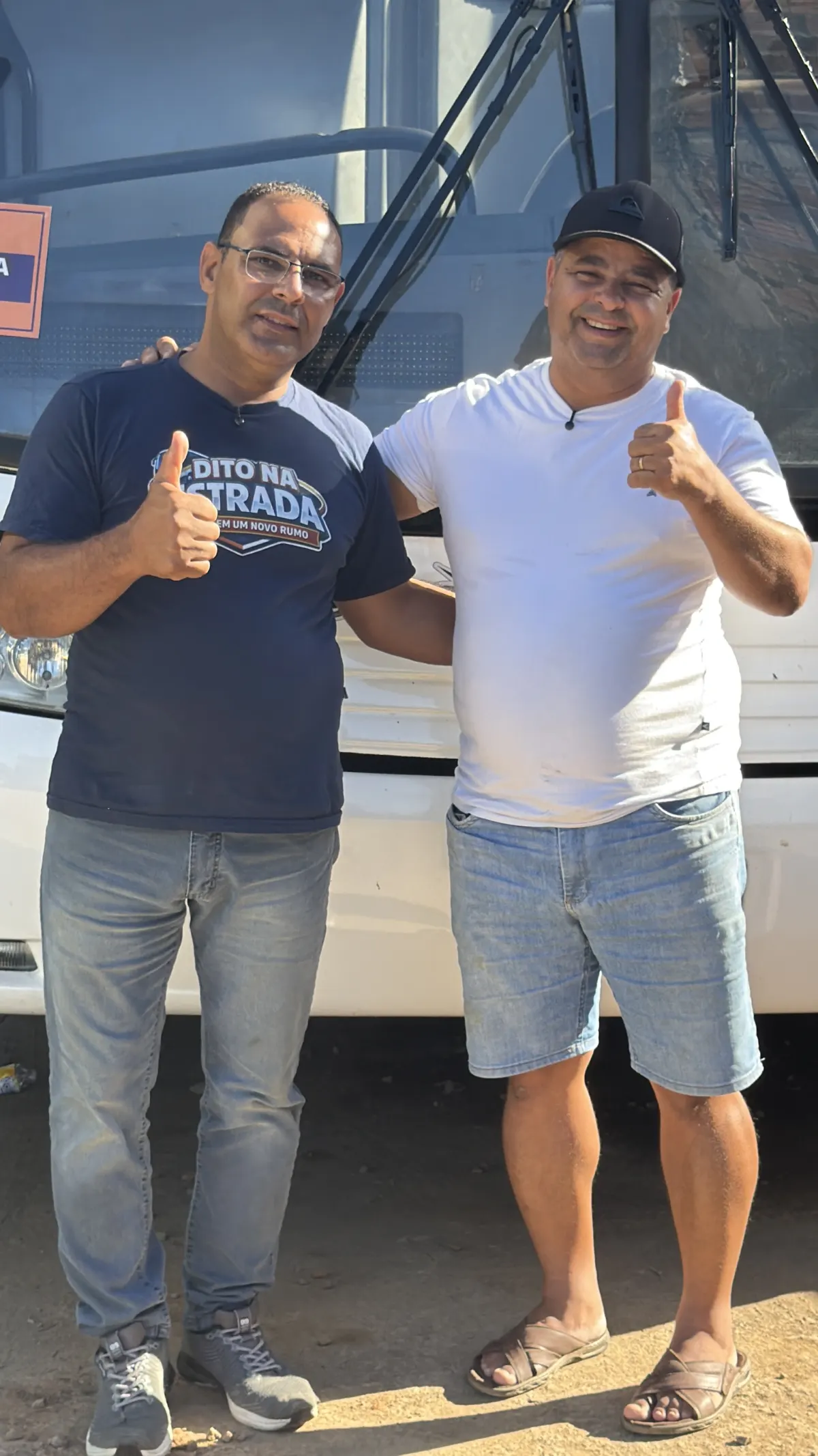 Dito conversando com um trabalhador em frente a um ônibus
